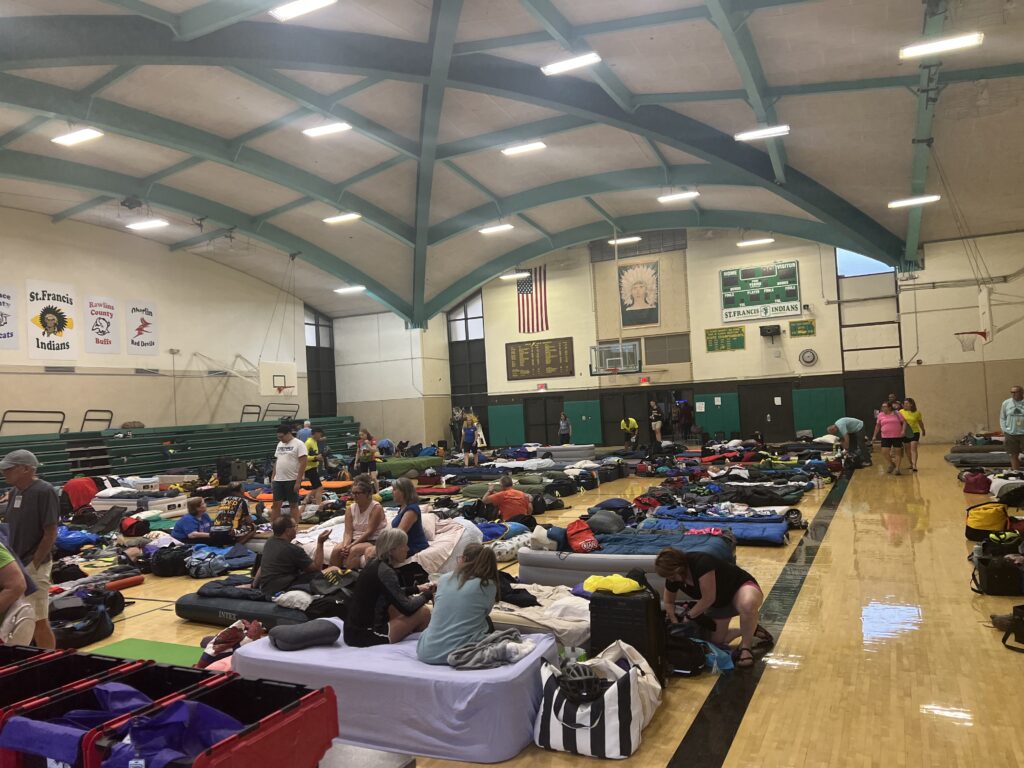 Bike Across Kansas participants resting and sleeping in the high school gymnasium after a long day on the road.