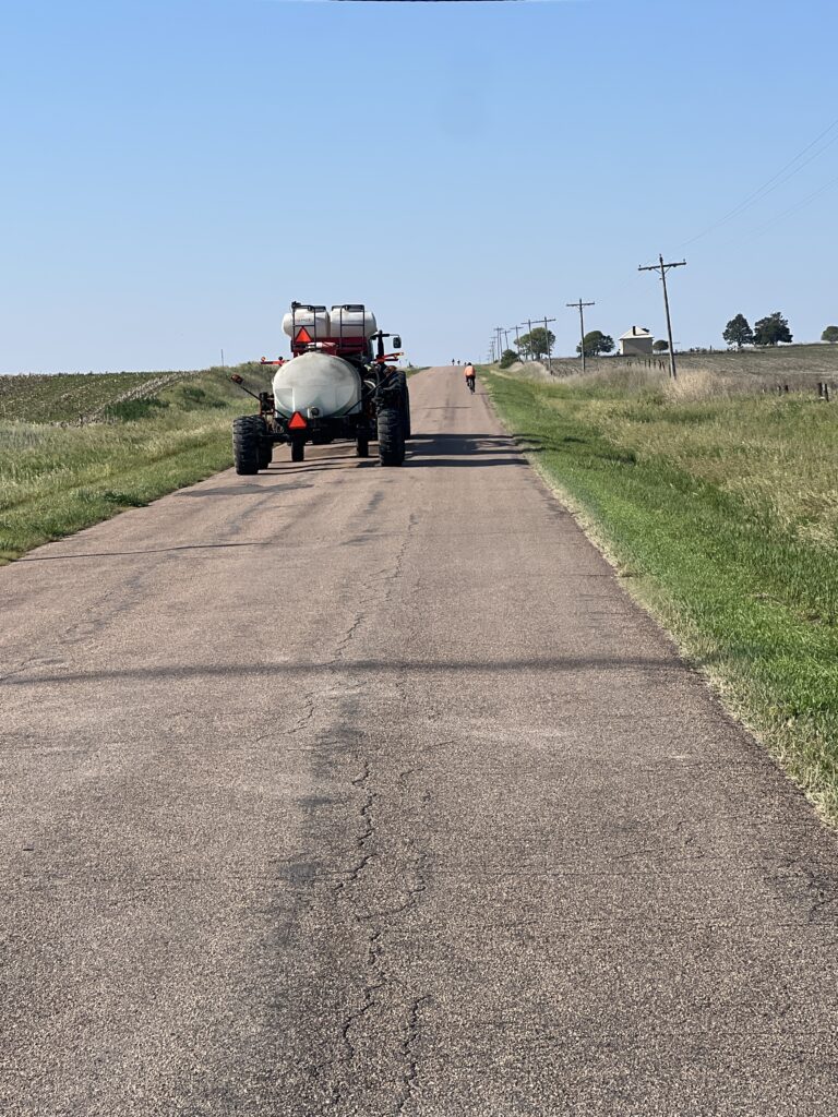 Kansas highway with farm equipment traveling alongside, capturing rural life and shared roads on the plains.