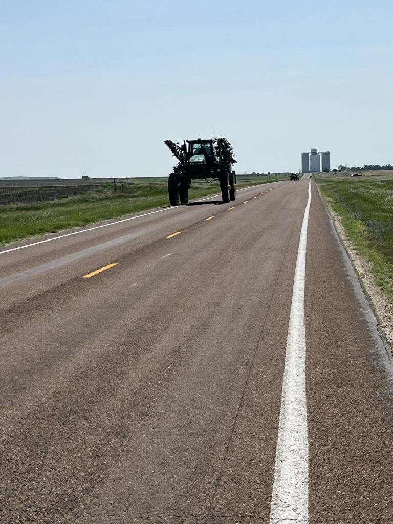 Tractor traveling down the highway alongside cyclists on a rural road”