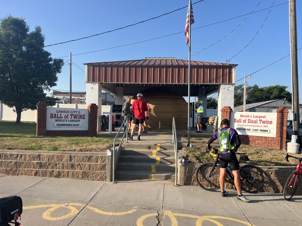 Massive ball of sisal twine resting under a covered pavilion in Cawker City, Kansas, showcasing layers of tightly wound twine in a quirky roadside attraction.
