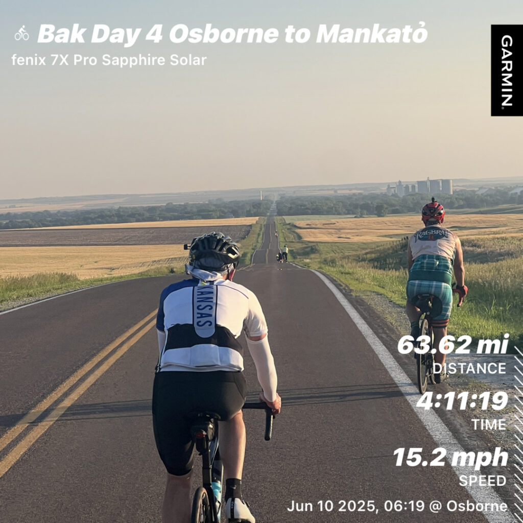 Cyclist riding through the open Kansas landscape at sunrise, surrounded by golden wheat fields and a hint of early morning mist—classic prairie serenity.
