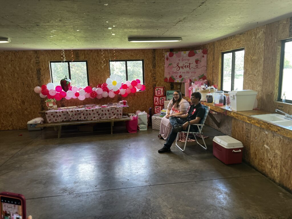 Marla and Brylan sitting together at their baby shower, surrounded by balloons and gifts, ready to celebrate Baby Brinlee — a ShauneNation moment to remember.