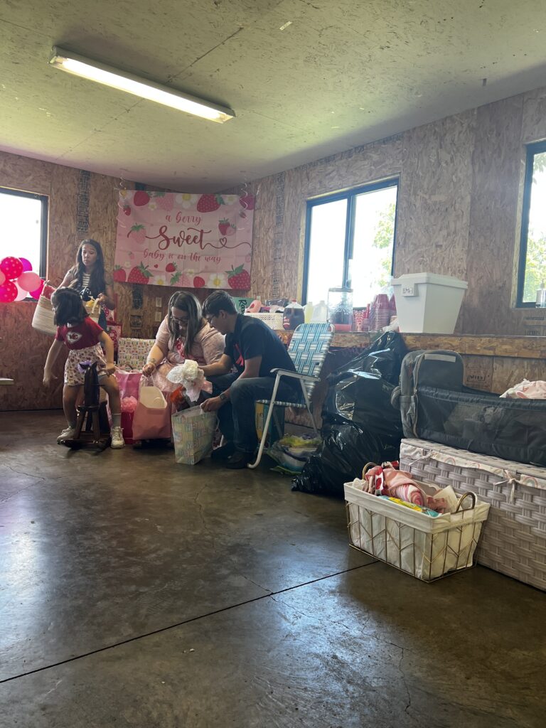 Marla and Brylan smiling as a young girl rides the new rocking horse at the baby shower.