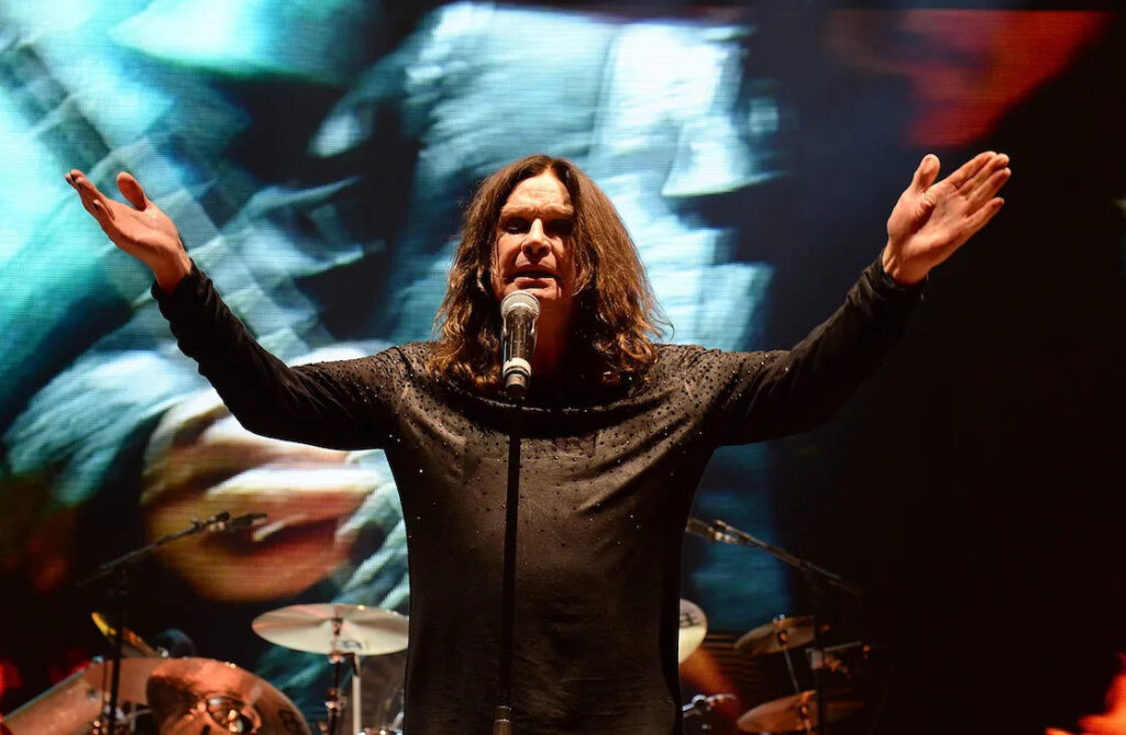 Ozzy Osbourne standing on stage with arms spread wide like an eagle