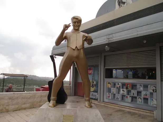 Statue of Elvis Presley standing with guitar, symbolizing his lasting cultural legacy.
