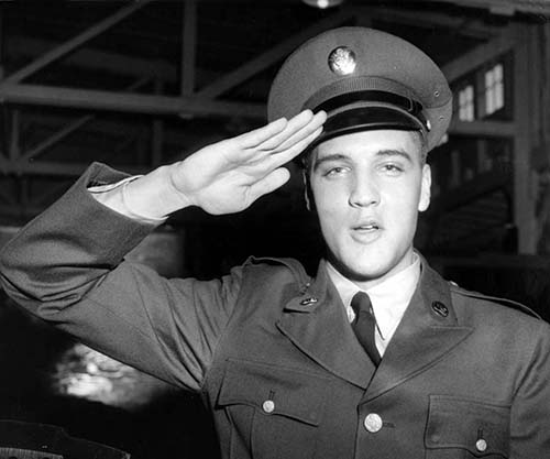 Elvis Presley in U.S. Army uniform, saluting while stationed in Germany, showing his service and dedication.