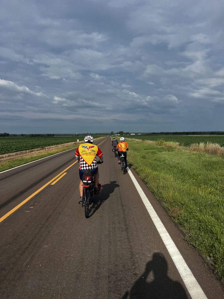 Cyclists riding on Kansas Highway 31 with no shoulder, surrounded by open countryside
