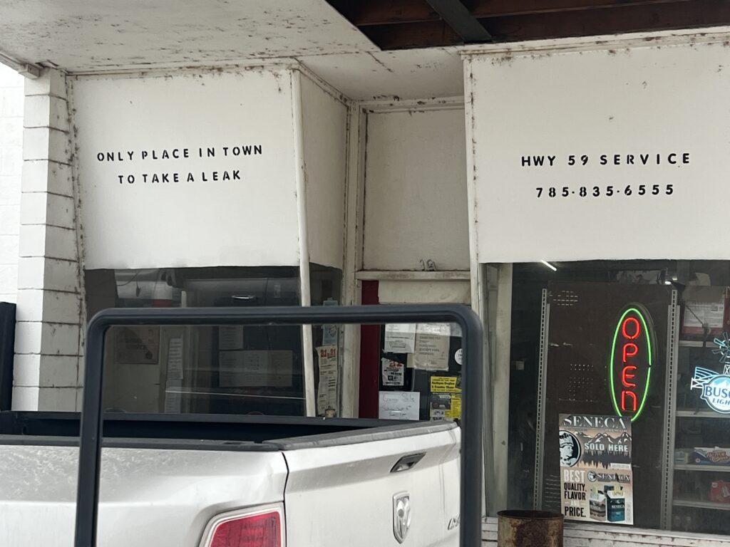 Front of Highway 59 Service, an old-time gas station in Richmond, Kansas, with a humorous sign by the door.