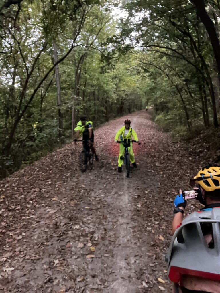 Cyclists ride the Katy Trail in the Clifton area, Missouri, in raincoats with wet leaves falling around them.