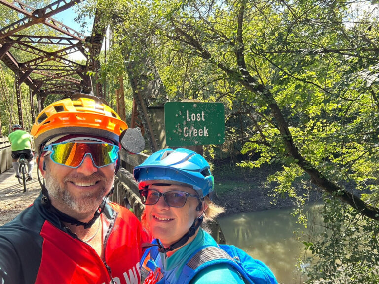Larabe and his wife Tammy standing in front of the Lost Creek Bridge sign during a ShauneNation bike ride