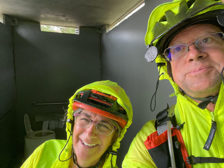 Dave and Kara taking a selfie inside a concrete outhouse during a Missouri rainstorm