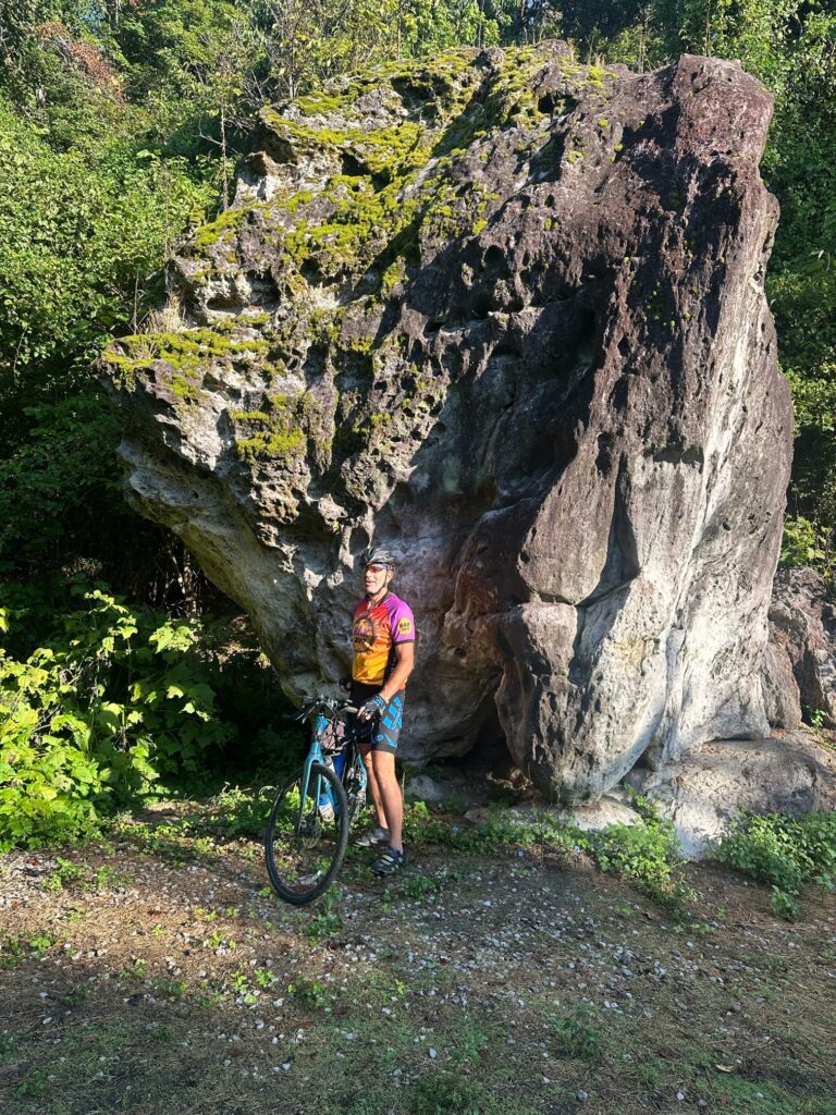 Rob standing in front of a massive rock along the Katy Trail, with marks showing past river floods.
