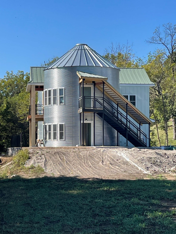 Unique silo-style building with stairs, upstairs and downstairs, and a house behind it, along the Katy Trail.