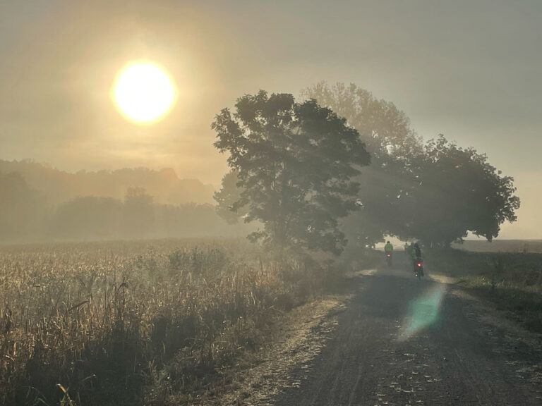 Bikers approaching trees on the Katy Trail outside Marthasville, Missouri, with morning fog and sunshine, captured on a ShauneNation ride