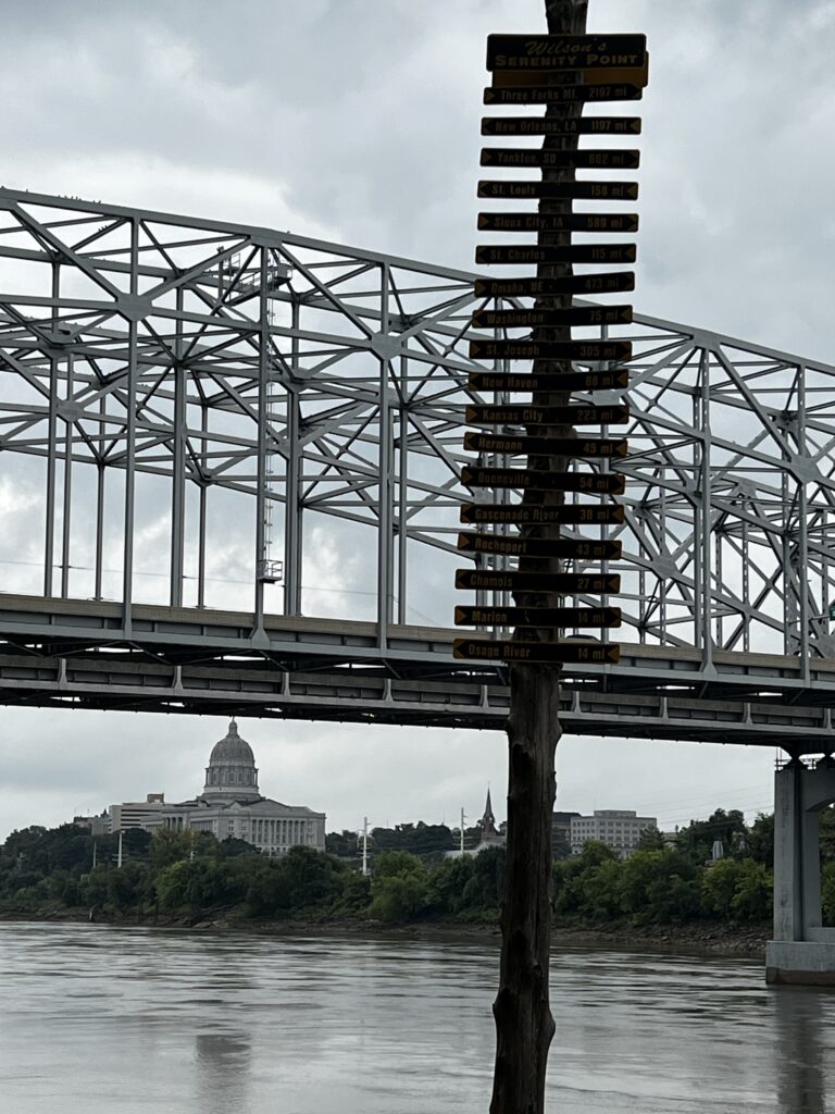 View of the Missouri River with mile marker pole and the state capitol under the bridge in Jefferson City