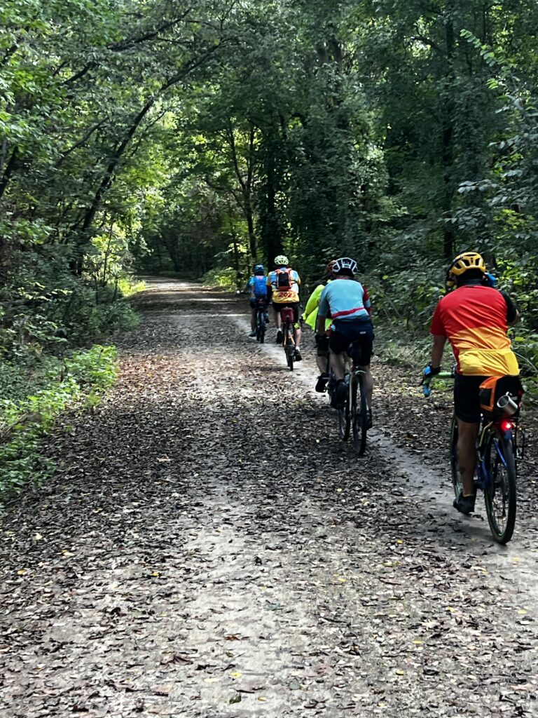 Katy Trail bicyclists lined up under trees, starting their ride from Tibbetts, Missouri.