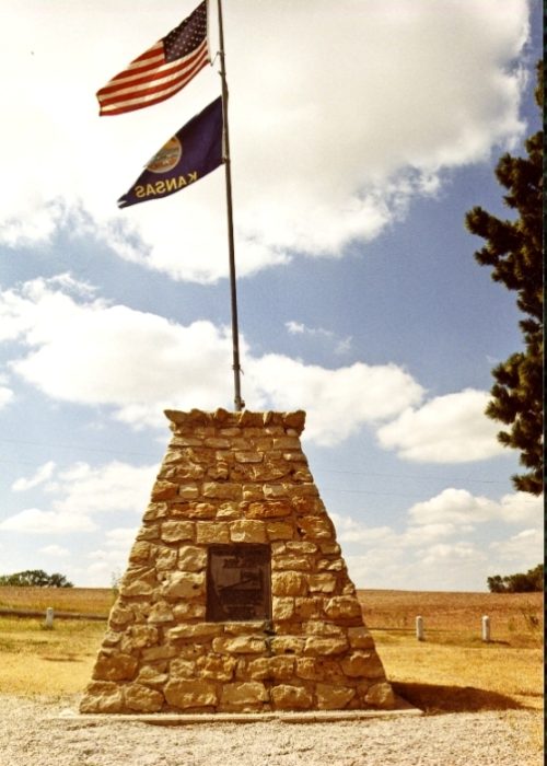 Two flags and a brick plaque marking the Geographical Center of the Contiguous United States near Lebanon, Kansas, visited by Shaune and riding partner during a Bike Across Kansas detour.