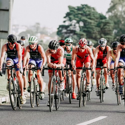A group of cyclists riding closely together on a road, moving in unison as if in a race or organized ride.